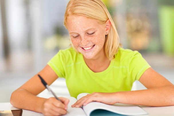 happy preteen girl writing homework - Foto, afbeelding