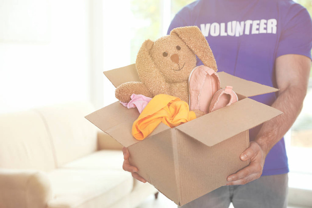 Доброволец держит коробку с пожертвованиями в помещении. Пространство для текста
 - Фото, изображение