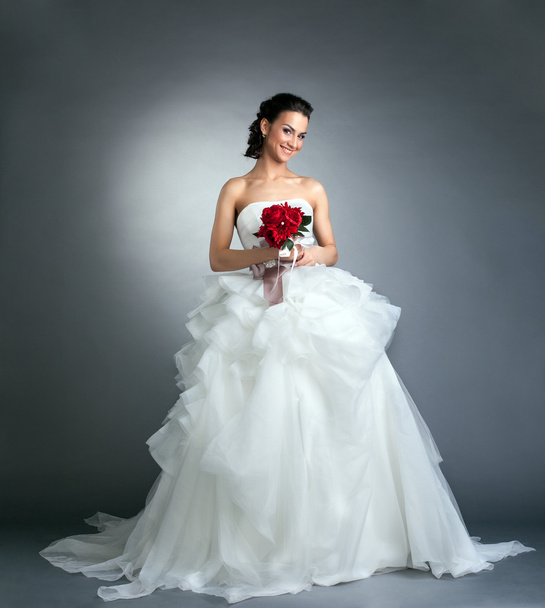 Charming bride with bouquet posing in studio - 写真・画像
