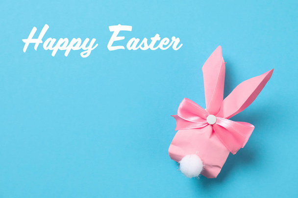 Creative bunny gift bag and text Happy Easter on color background, top view - Фото, изображение