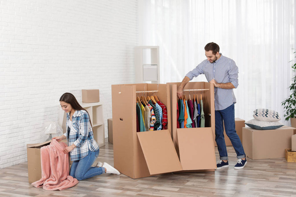 Young couple near wardrobe boxes at home - Foto, imagen