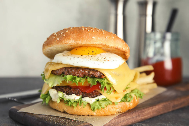 Tasty burger with fried egg on wooden board - Photo, Image
