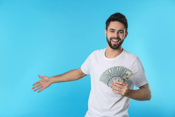 Portrait of happy young man with money on color background. Space for text - Fotografie, Obrázek