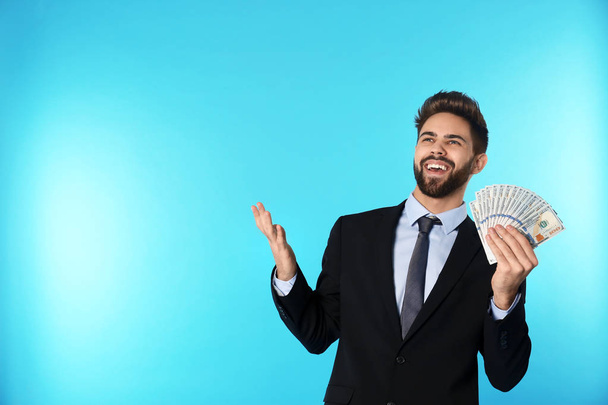 Portrait of happy young businessman with money on color background. Space for text - Фото, изображение