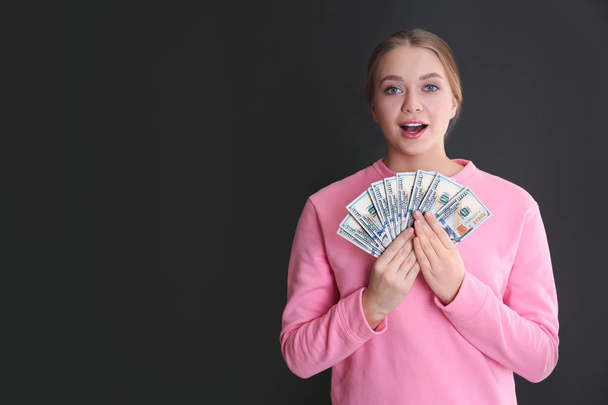 Portrait of emotional young woman with money on grey background. Space for text - Valokuva, kuva