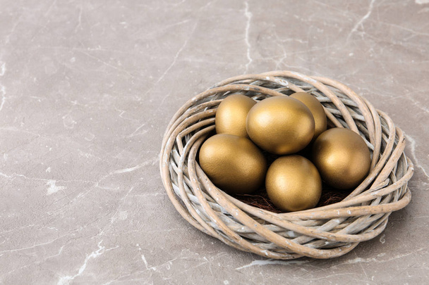 Golden eggs in nest on color background, space for text - 写真・画像