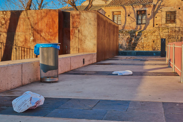 Muovipussien ja roskien jäännökset ja roskakori auringonnousun aikaan puistossa Toledossa Espanjassa
 - Valokuva, kuva