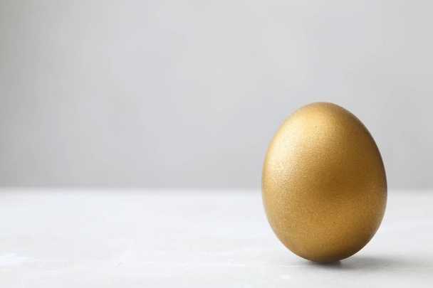 One shiny golden egg on table, space for text - Foto, Imagem