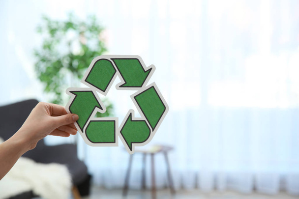 Woman holding recycling symbol on blurred background, closeup. Space for text - Photo, image