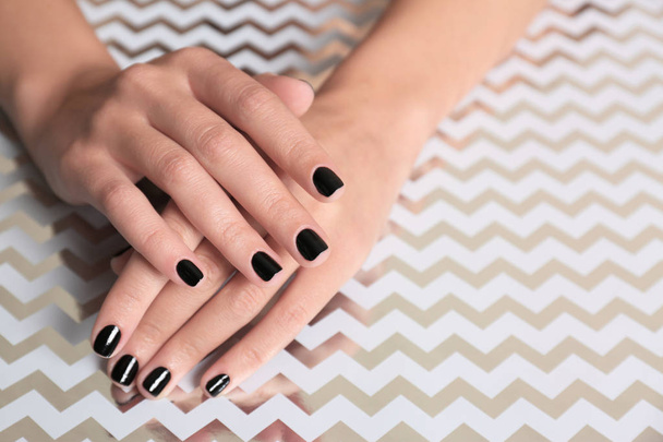 Woman showing black manicure on shining background, closeup with space for text. Nail polish trends - Fotó, kép