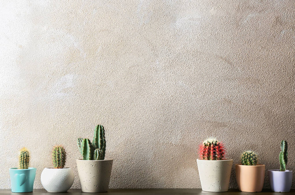 Different potted cacti on table near color background, space for text. Interior decor - Photo, image