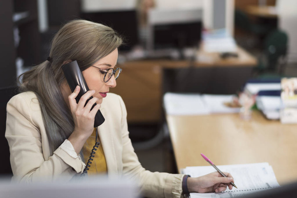 Attractive 30s woman working at office with telephone - 写真・画像
