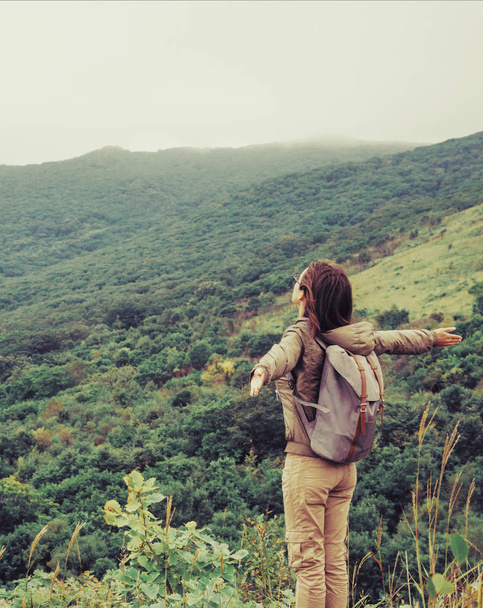 Onnellinen reppumatkailija nuori nainen seisoo vuorilla
. - Valokuva, kuva