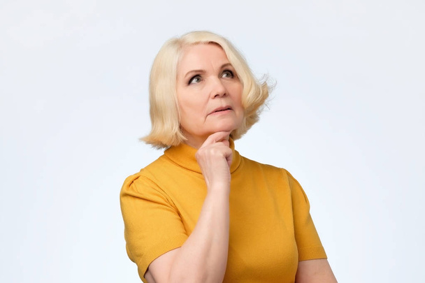 Senior blonde vrouw opzoeken en denken - Foto, afbeelding