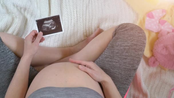 pregnant woman holding ultrasound photos of fetus - Filmati, video