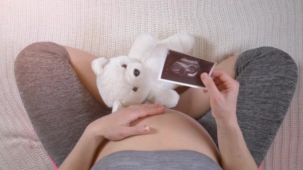 pregnant woman holding ultrasound photos of fetus - Filmati, video