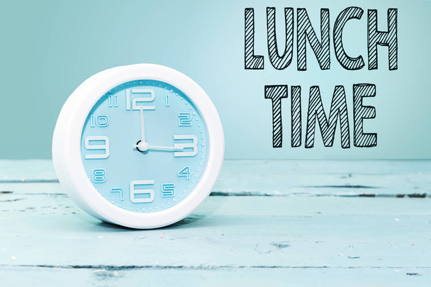 despertador mostrando doze horas em mesa de madeira azul. conceito de hora de almoço
 - Foto, Imagem