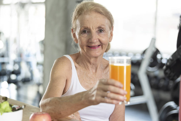 Mujer mayor comiendo ensalada saludable y jugo de naranja
.  - Foto, imagen