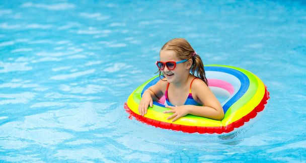 Child in swimming pool on toy ring. Kids swim. - Photo, image