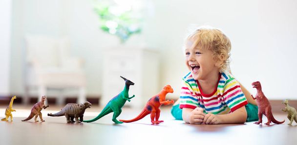 Το παιδί παίζοντας με toy δεινοσαύρων. Παιδικά παιχνίδια. - Φωτογραφία, εικόνα