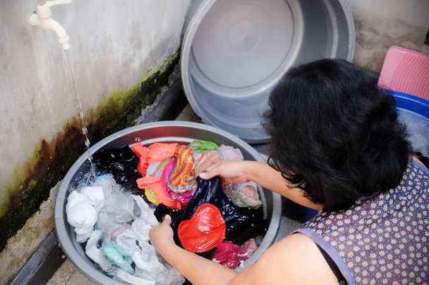 Азиатская женщина стирает одежду для рук дома
 - Фото, изображение