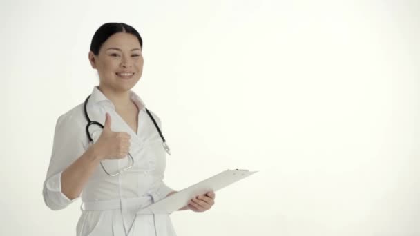 Asian Nurse on White Background Smiles and Lifts Thumb. - Video