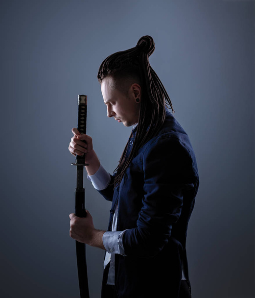 Νεαρός άνδρας που κρατάει ένα σπαθί σαμουράι. Φωτογραφία αίγλη. - Φωτογραφία, εικόνα