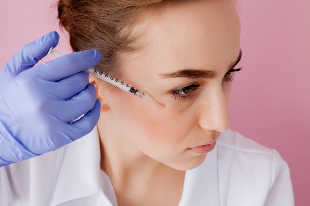 The doctor cosmetologist makes the Botulinotoxin injection procedure for tightening and smoothing wrinkles on the face skin of a beautiful, young woman in a beauty salon.Cosmetology skin care - Zdjęcie, obraz