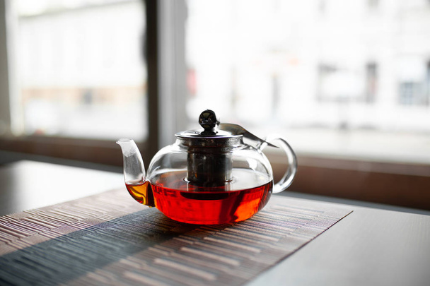 Glass teapot of invigorating fresh aromatic tea on a wooden - Фото, изображение