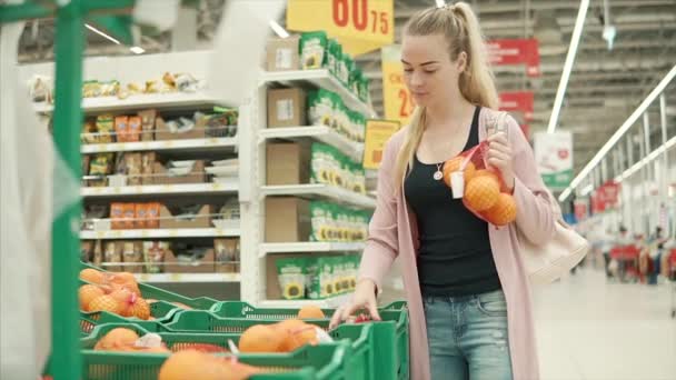 Jonge blonde vrouw is het nemen van pakketten met sinaasappelen in een supermarkt - Video