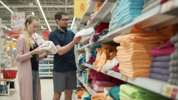 Spouses are deciding which color of towels to buy in shop, examining assortment - Footage, Video