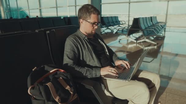 Seul passager masculin attend son vol dans un terminal et navigue dans un ordinateur portable
 - Séquence, vidéo