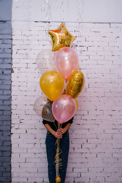 young woman holding colorful balloons and posing on brick wall studio background , birthday concept  - Foto, imagen