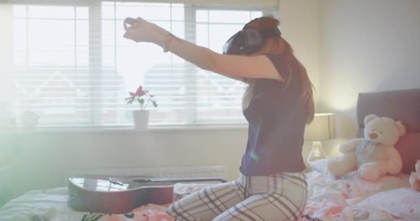 Very enthusiastic young lady in her comfortable bed playing with a VR and very concentrated she exploring the virtual gaming world. - Filmmaterial, Video