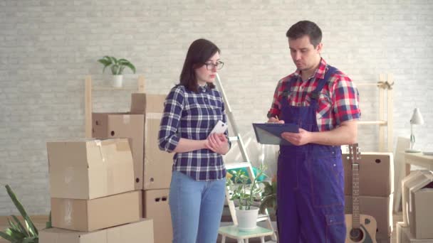 loader in uniform and young woman on the background of boxes for moving new home - Filmmaterial, Video