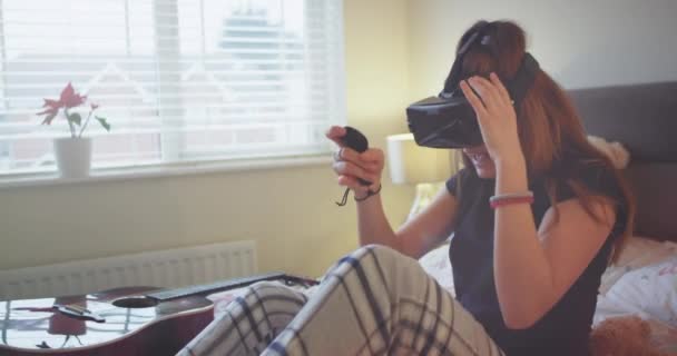 Portrait of a young teenager girl in a pajamas playing with a VR she are very impressed about the game and exploring the world game. - Filmagem, Vídeo