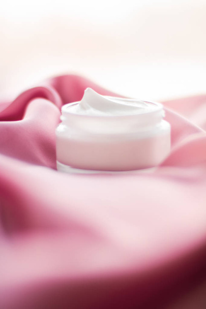 Frasco de creme de rosto luxuoso em uma seda rosa suave
 - Foto, Imagem