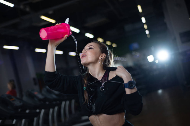 Girl after a workout drinking water in the gym - Zdjęcie, obraz