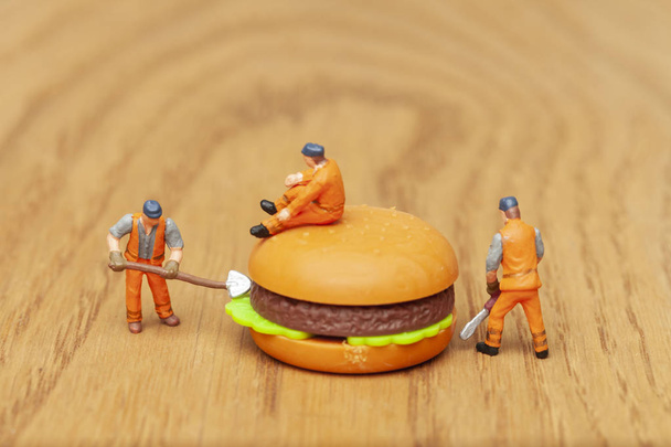 Ungesundes Ernährungskonzept mit Miniaturmenschen und Fast Food - Foto, Bild
