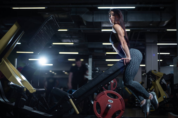 Фітнес дівчина позує в спортзалі, показує її тіло і розслабляється після тренування
 - Фото, зображення