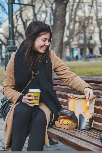 リヴィウ、ウクライナ - 2019 年 2 月 28 日: 女性市ベンチにファーストフードを食べる - 写真・画像