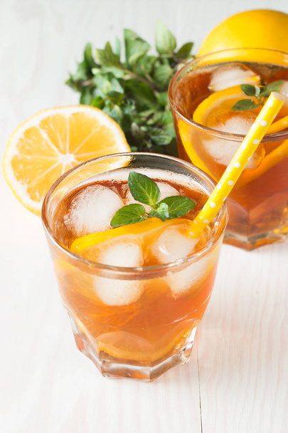 Refreshing citrus lemonade, summer drink. Ice tea with fresh lemon and mint on wooden background. Refreshment beverage concept. - Photo, Image