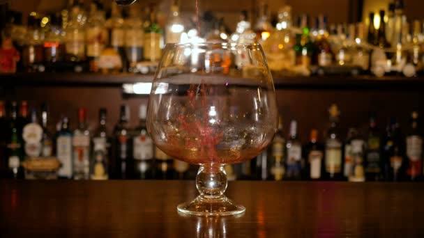 Горячее вино наливают в большой стакан на заднем плане барной стойки с бутылками. Приготовление глинтвейна
. - Кадры, видео