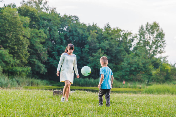 Äiti pelata pojan kanssa pallo vihreällä kentällä
. - Valokuva, kuva