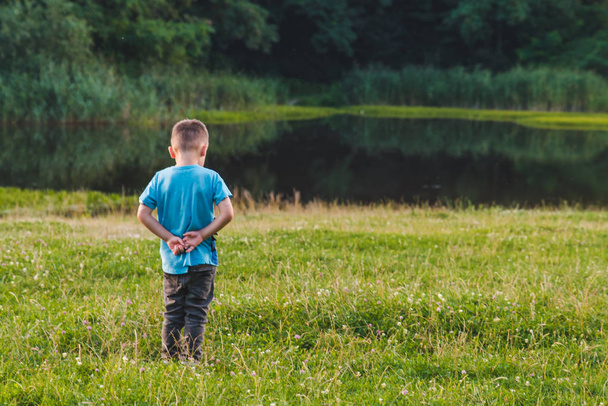 маленький обиженный мальчик стоит в стороне в одиночестве
 - Фото, изображение