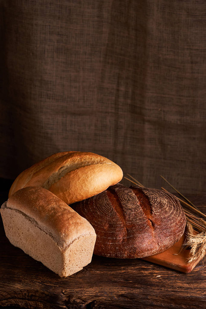 Хлібобулочні вироби - золотий сільський хліб з хліба та булочок на чорному крейдяному фоні. Натюрморт, захоплений зверху
 - Фото, зображення