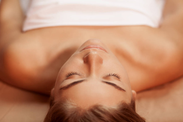Top view close up shot of a young gorgeous woman with flawless unblemished skin, lying on massage table at spa center. Beautiful woman resting after spa treatment. Skincare, youth, beauty concept - Foto, Imagem