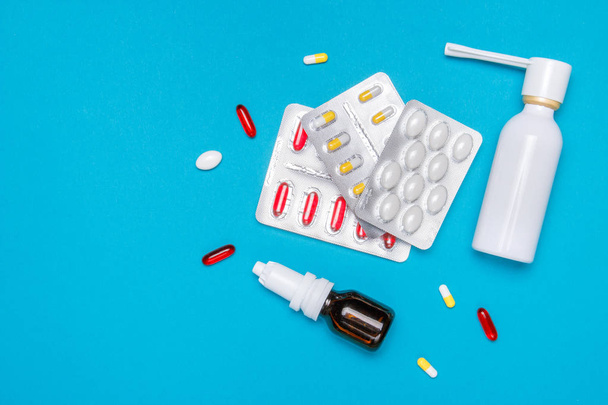 Treatment of colds and flu. Various medicines, sprays from a stuffy nose and a pain in a throat on a blue background. Copy space. Medicine flat lay. - Photo, Image