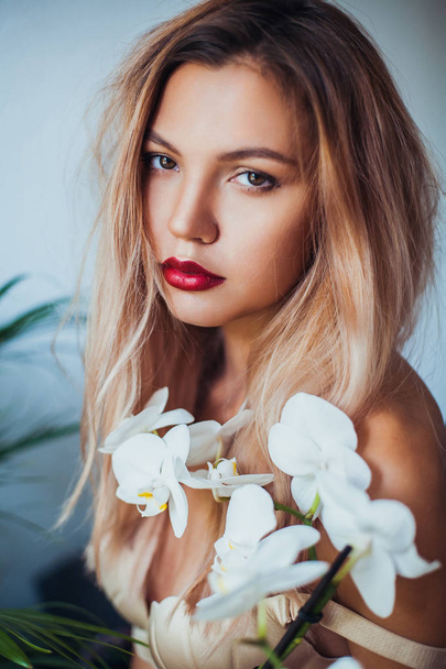 Muoti kuva kaunis tyttö tilalla valkoinen orkideat
. - Valokuva, kuva