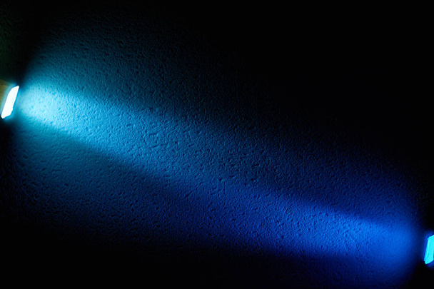 Op een zwarte achtergrond, licht blauwe stralen van lichte glans ten opzichte van elkaar - Foto, afbeelding